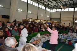 Hombre mostrando cómo cortar cerdo ibérico a un grupo de personas en un evento.