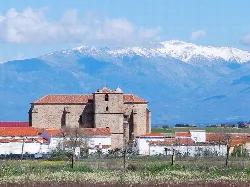 Stone church in Saucedilla with snow-capped mountains.