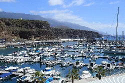 Port with many boats and mountains in the background.