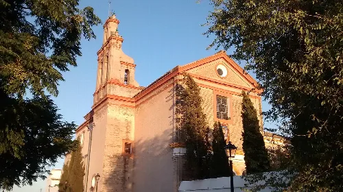 Fachada del monasterio con árboles y cielo azul.