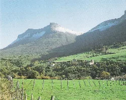 Montañas y casas en un valle con campos verdes.