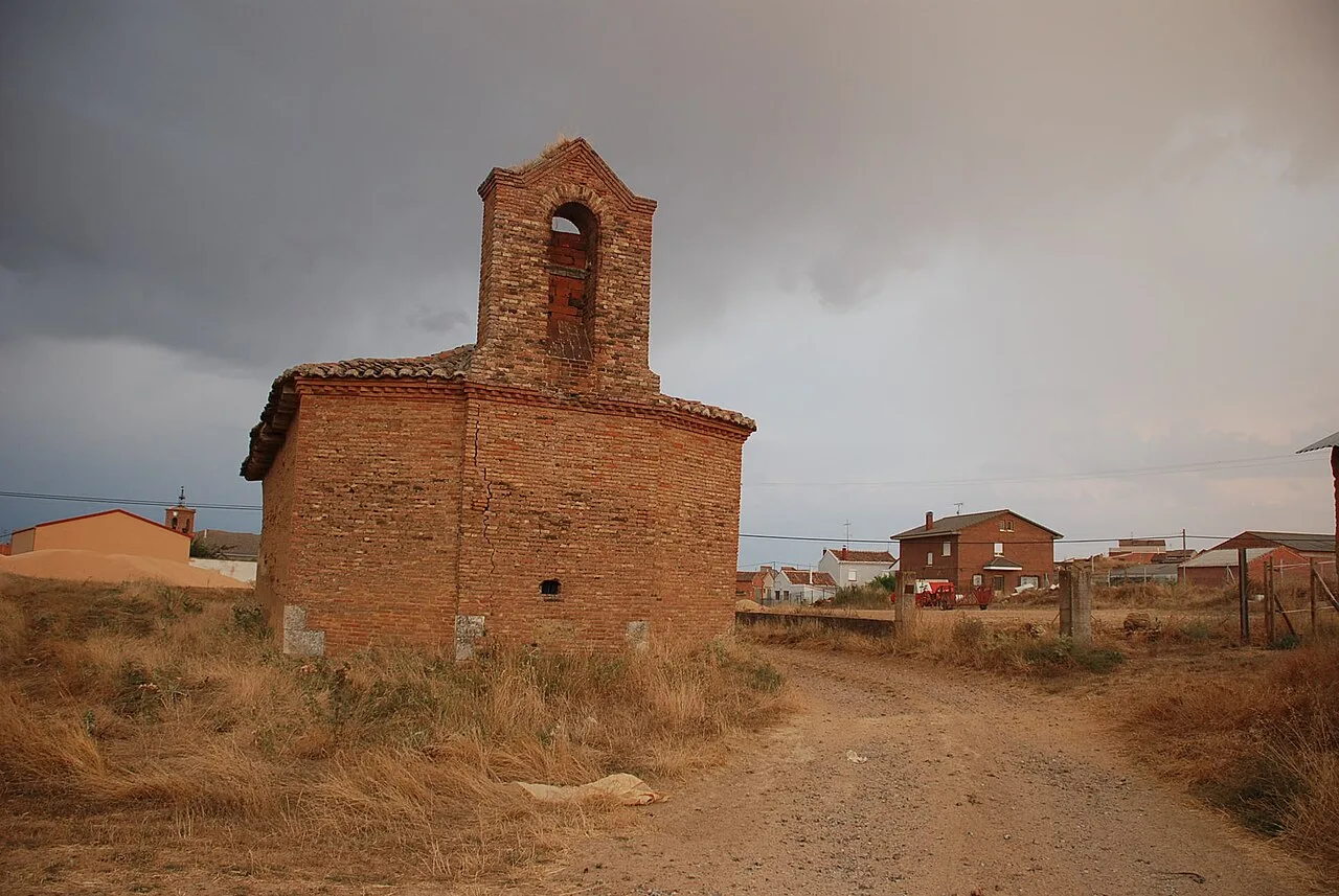 Pequeña iglesia de ladrillo con campanario en un paisaje rural.
