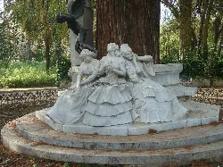 Sculpture of three women on a bench in Seville park.