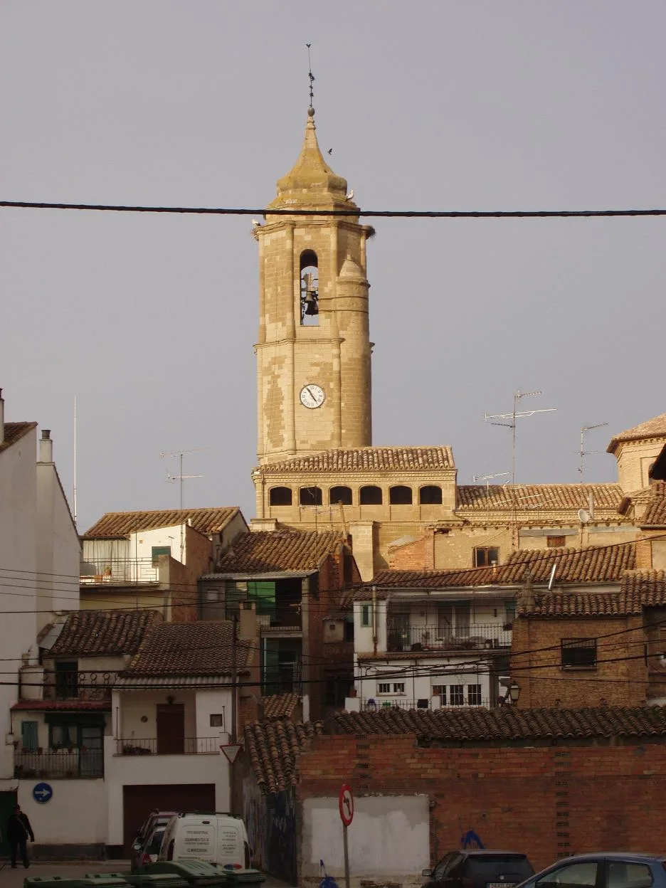 Torre de la iglesia y casas en Binéfar, con tejados y reloj en la torre.