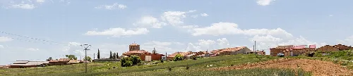 Landschaft von Fuentearmegil mit Häusern und bewölktem Himmel.