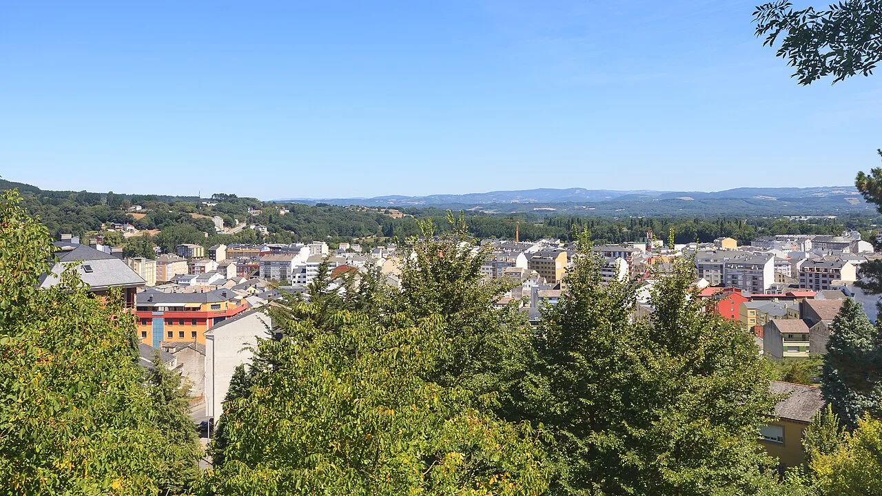 Vista de la ciudad de Sarria con edificios y árboles.
