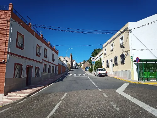Calle en Villaharta con edificios blancos y cielo azul.