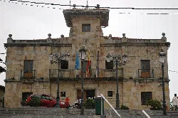 Stone building with flags and street lamps on the facade.