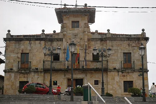 Edificio de piedra con banderas y farolas en la fachada.
