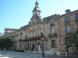 Historic building with clock tower and flags on the facade.