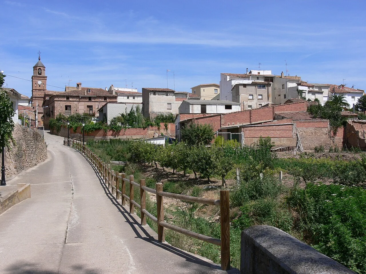 Camino con valla de madera y casas al fondo en Bergasa.
