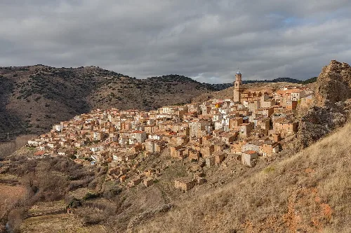 Panoramic view of Moros village in Zaragoza, with houses on the hillside and a church at the top.