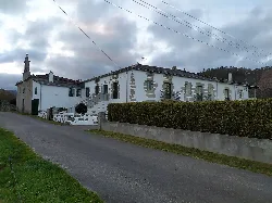 Hauptfassade des Pazo de Rizal mit Mauer, Balkonen und Kapelle in Alfoz.