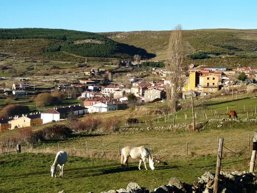 Ländliche Landschaft mit Häusern, Pferden und Hügeln in Hoyos del Espino.