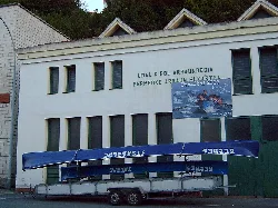 Building with a sign and rowing boats stacked outside