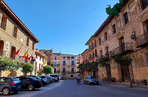 Plaza con edificios antiguos, árboles y coches estacionados en Cintruénigo.