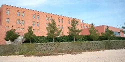 Lateral view of a hospital with trees and wall in front.