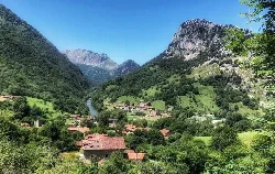 Landscape with houses, river, and green mountains in Peñamellera Alta.