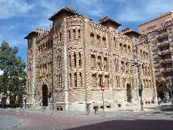 Edificio de Correos de Castellón de la Plana, de estilo neomudéjar, en una plaza con árboles y edificios modernos.