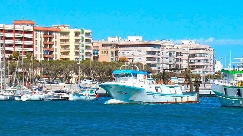 Barcos en el puerto de Adra con edificios modernos detrás.