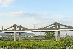 Moderner Viadukt über grünen Feldern und Himmel mit Wolken.