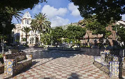 Square with palm trees, benches, and historic buildings in Santa Cruz de Tenerife.