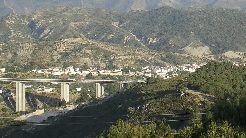 Landschaft mit Bergen, Vegetation und Autobahn im Vordergrund.