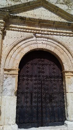Puerta de madera con adornos en arco de piedra en Loranca de Tajuña.