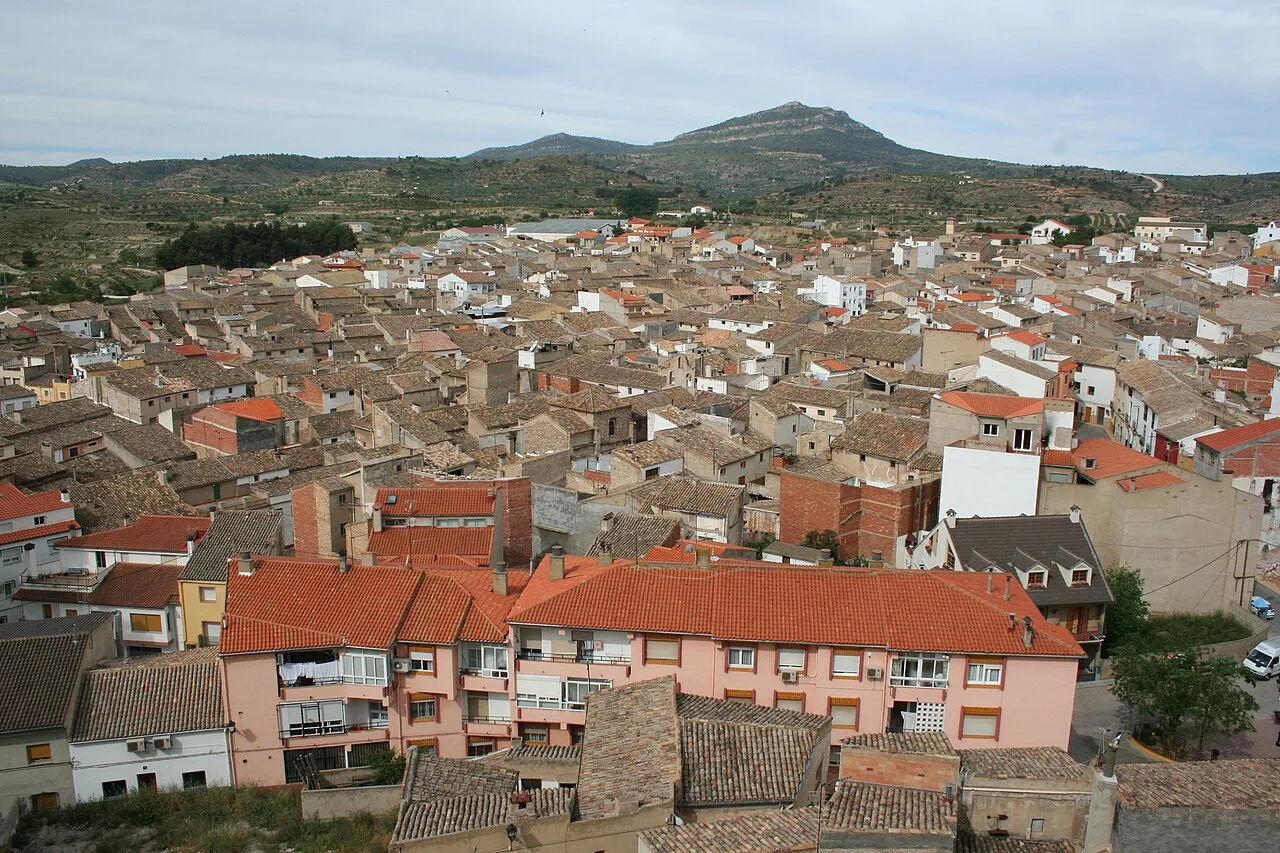 Vista de tejados y casas en Ayora, Valencia, con colinas en el fondo.