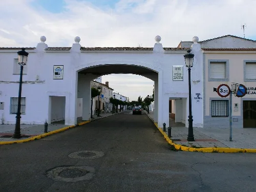 Entrada principal a Pueblo Nuevo del Guadiana con su escudo a la izquierda del arco.