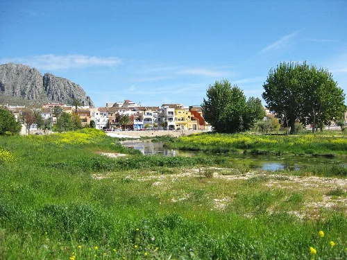 Aussicht auf den Fluss Girona, Beniarbeig und das Segària-Gebirge mit Bäumen und Häusern.