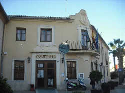 Edificio del ayuntamiento de Museros con banderas y cartel en la fachada.