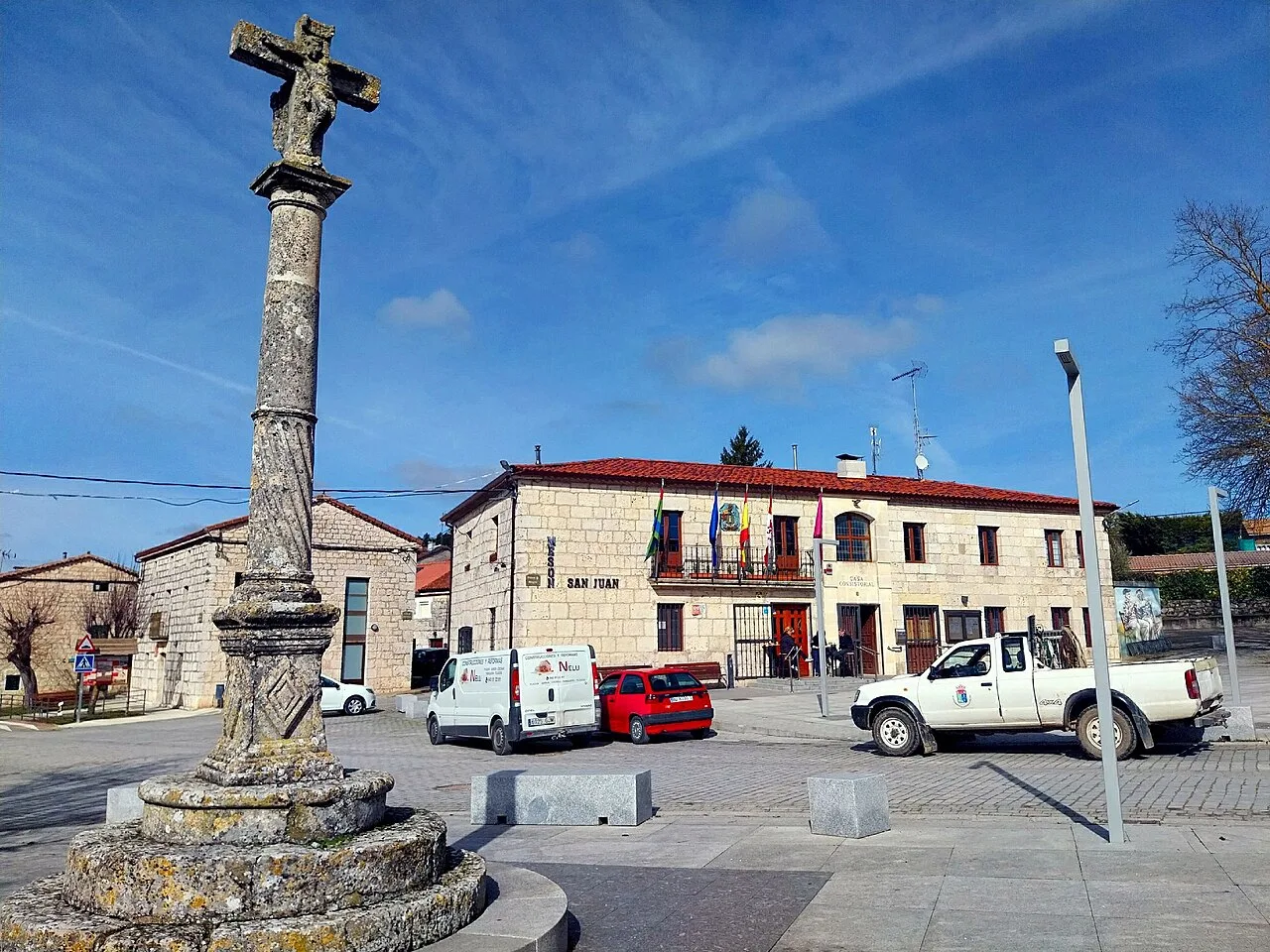 Main square with an old cross and buildings in Castrillo del Val.