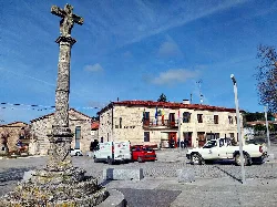 Main square with an old cross and buildings in Castrillo del Val.