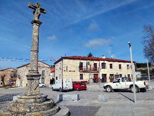 Main square with an old cross and buildings in Castrillo del Val.