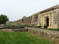 Stone walls and gate in Roses, with grass and a path in front.