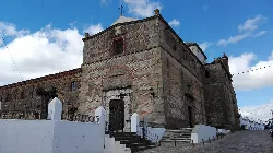 Stone church facade with stairs and cloudy sky.