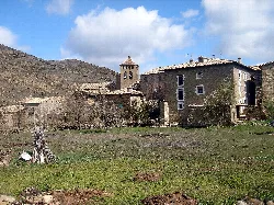 Vista de casas antiguas y una iglesia en Longás con montañas al fondo.