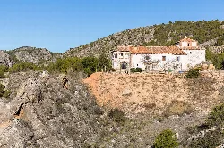 San Daniel's hermitage on a hill with mountains in the background.