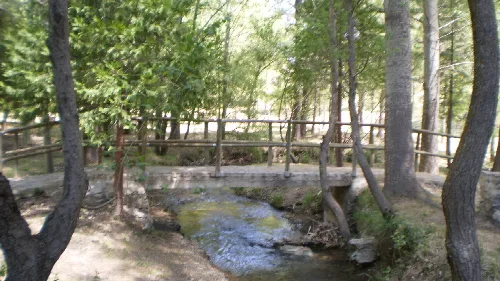 Kleiner Fluss mit Holzbrücke in bewaldeter Gegend in Las Santas, Huéscar.