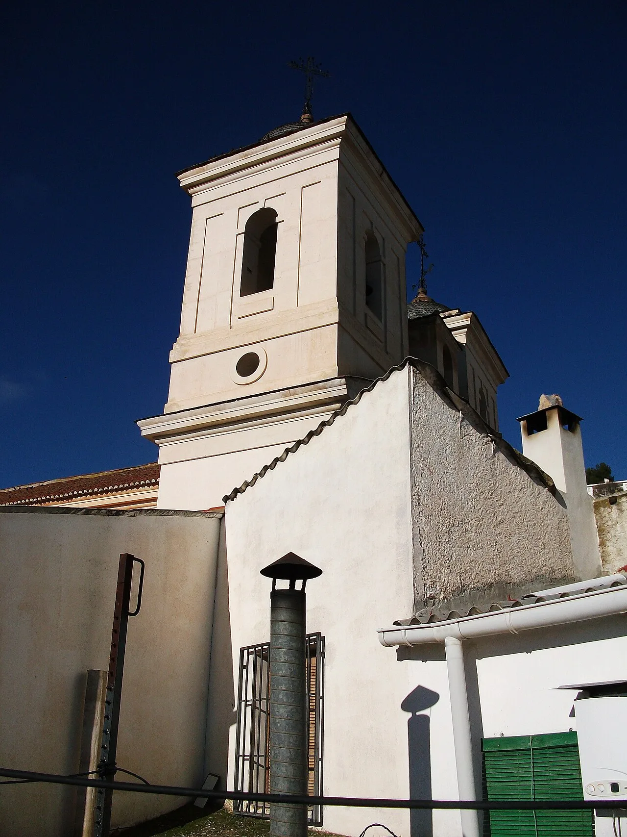 Iglesia blanca con torre neoclásica y cielo azul.