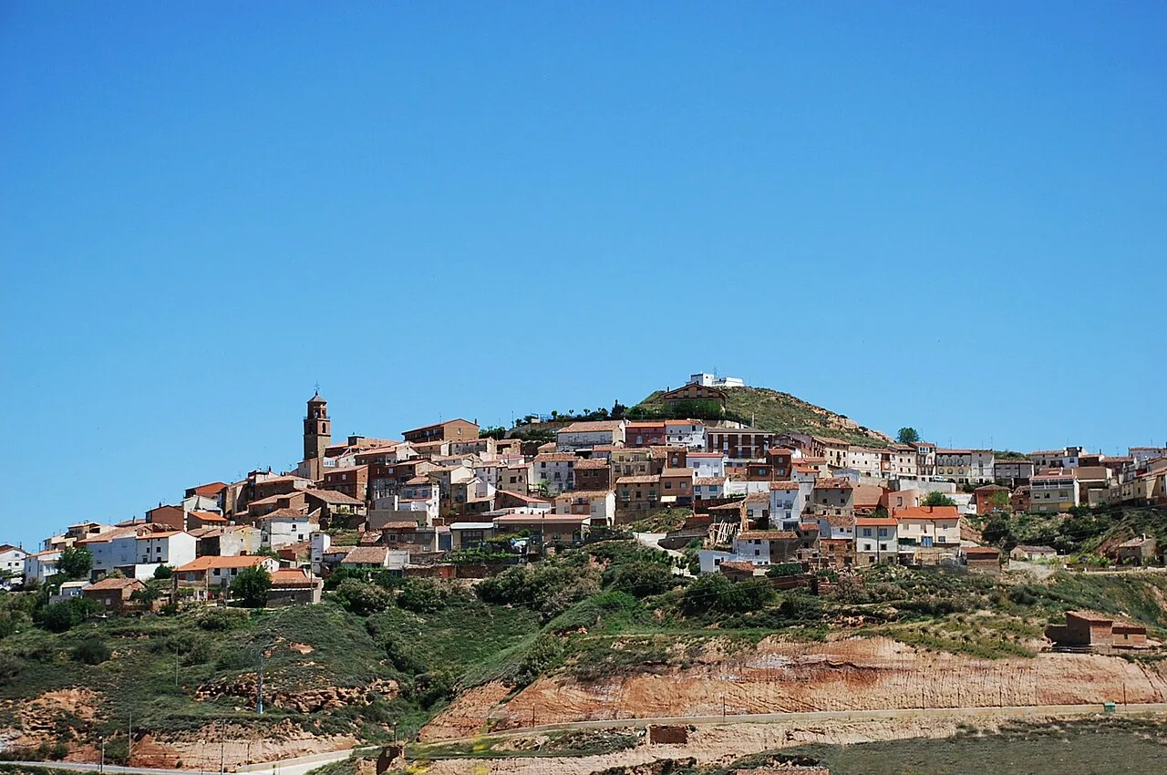 Vista panorámica de Ausejo con casas y colinas bajo un cielo azul.