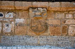 Coat of arms and plaque on an old house wall in Riotuerto.
