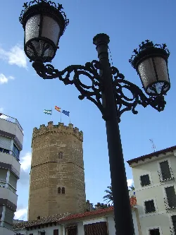 View of the castle tower of Porcuna from La Farola with a street lamp in the foreground.