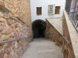 Steinernes Treppenhaus mit Metallgeländern, das zu einer alten Wasserzisterne in Soneja führt.