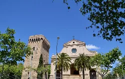 Old tower and church with palm trees and green trees in Cambrils.