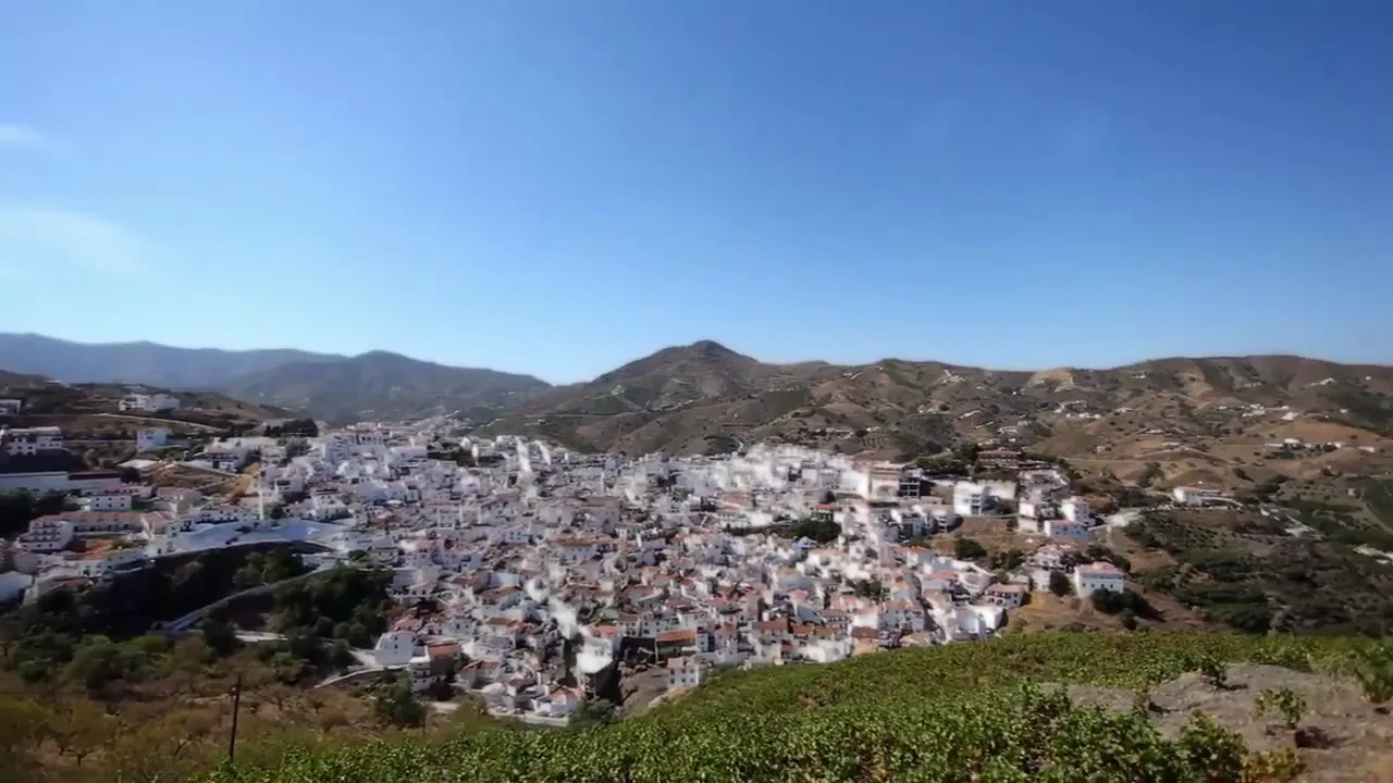 Vista aérea de Almáchar con casas blancas y montañas.
