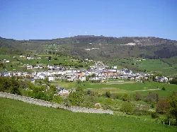 Paisaje con casas y colinas verdes en Boal, Asturias, con montañas y molinos de viento en el fondo.