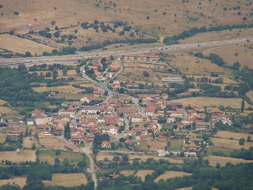Aerial view of a village with houses and roads in a rural landscape.
