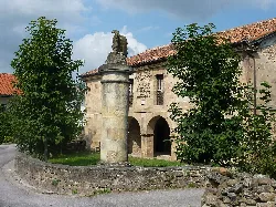 Stone heraldic pillar in Villafufre with trees and an old building.
